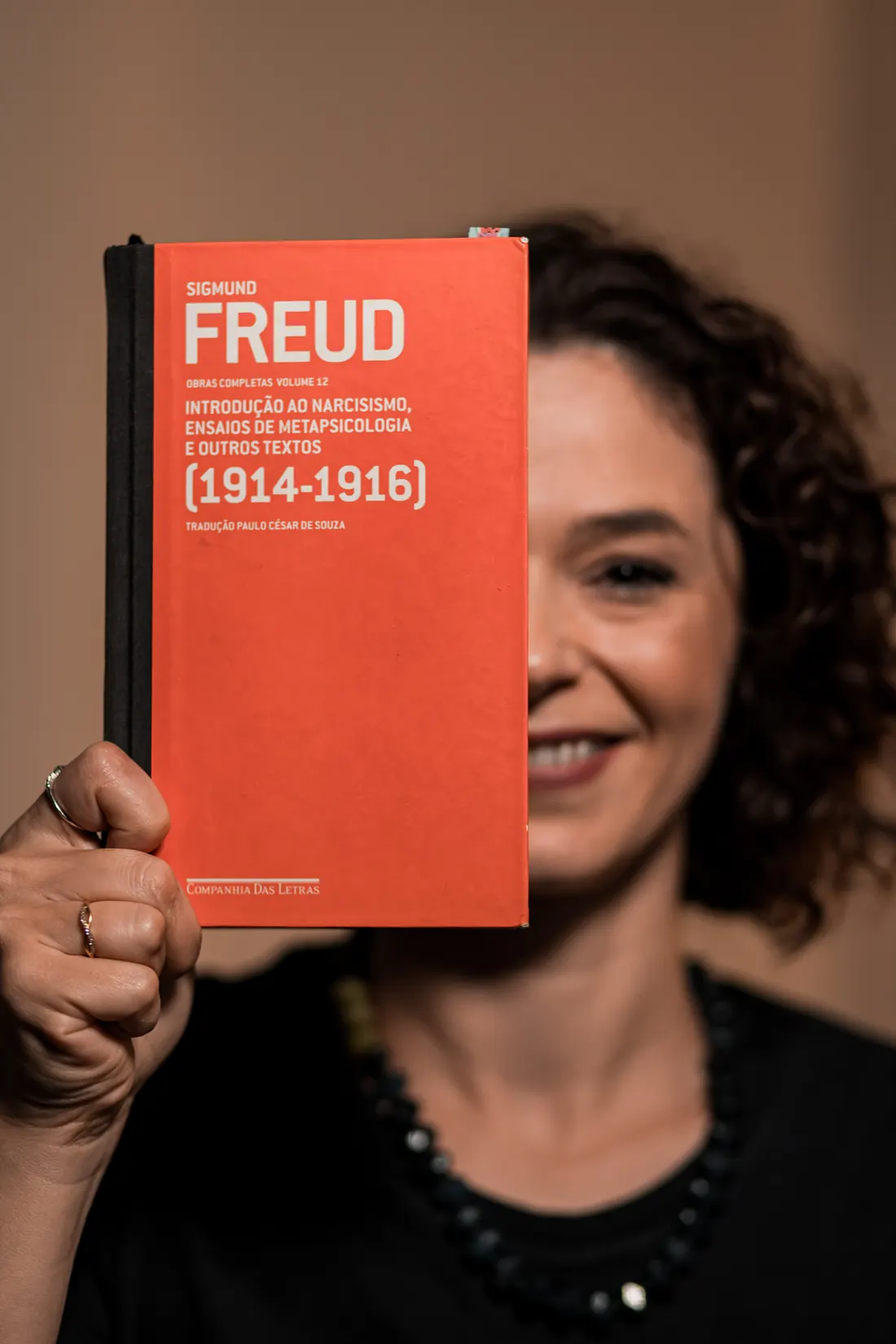 Bibiana Malgarim segurando o volume 12 das obras completas de Freud diante do rosto