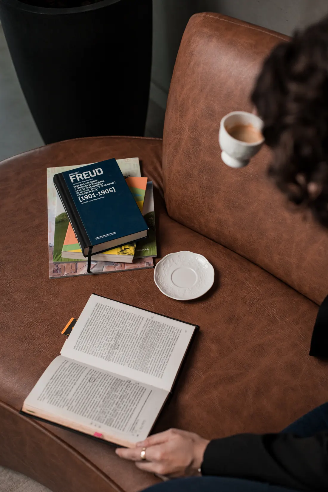 Volume das obras completas de Freud aberto, com anotações, ao lado de uma xícara de café